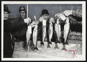 A group of unidentified people hold up fish