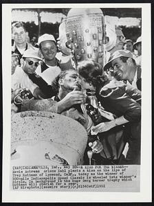 A Kiss For The Winner-- Movie Actress Arlene Dahl plants a kiss on the lips of Troy Ruttman of Lynwood, Calif., today as the winner of 500-mile Indianapolis Speed Classic is wheeled into winner's circle. In background is the huge Borg Warner trophy which Ruttman will cherish for a year.