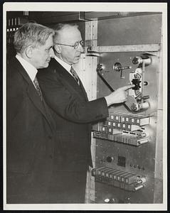 Explaining New Phone Weather Service. New York, N.Y.- Dr. James H. Kimball, New York meteorologist (left) and Ralph E. Walker, vice president of the New York Telephone Company, are pictured at the Weather Forecast Bureau which will be opened by the New York Telephone Company here, as the latter demonstrated an automatic device for giving weather information. Beginning at 12:01 A.M. tomorrow (April 8), New Yorkers may dial a number and hear the latest weather forecast spoken over the wire by a special voice recording and reproducing machine of the N.Y. Telephone Company. The number that will bring information as to whether it will be clear or cloudy, rainy, warmer or cooler, is weather 6-1212.