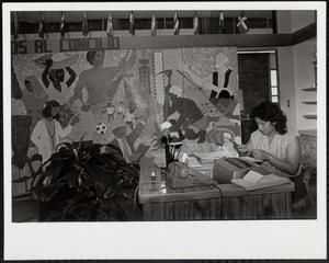 Woman sitting at a desk in front of wall mural