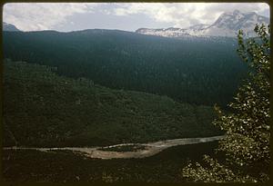 Narrow river at foot of hills and mountains