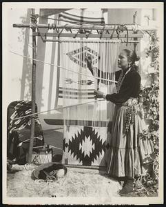 An Old Indian Custom - Na Glee Nona Ba ("Peacemaker" to You!) is Expert at Weaving Colorful Navajo Rugs Photo Shows: Na Glee Nona Ba (Peacemaker), a Navajo Indian Princess, weaving a rug in the patio of her home here. The Princess makers her winter home at America's most exclusive desert resort where she carries on the ancient traditions of her race. Weaving Rug
