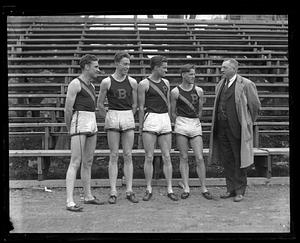 Four unidentified track athletes speaking to an unidentified man