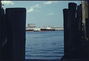 View of East Boston piers through gap in wharf