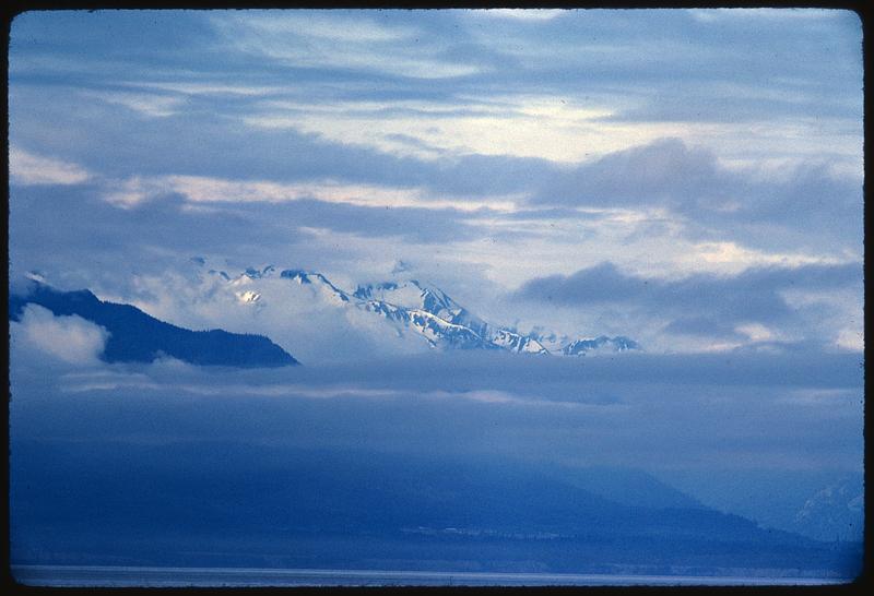 Sky-level view of clouds partly covering mountaintops