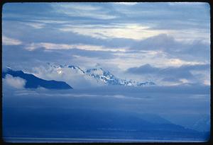 Sky-level view of clouds partly covering mountaintops