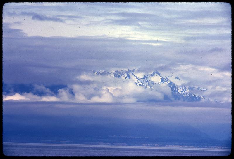 Sky-level view of clouds partly covering mountaintops