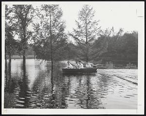 Keep To the Right-These youngsters keep to the right as they skim along over the flooded Neponset Valley parkway at Brush Hill road, Readville. The area was inundated yesterday when the Neponset river overflowed its banks.