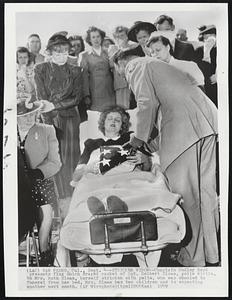 Stricken Widow--Chaplain Dudley Boyd presents flag which draped casket of Sgt. Delbert Sloan, polio victim, to Mrs. Ruth Sloan, herself stricken with polio, who was wheeled to funeral from her bed. Mrs. Sloan has two children and is expecting another next month.