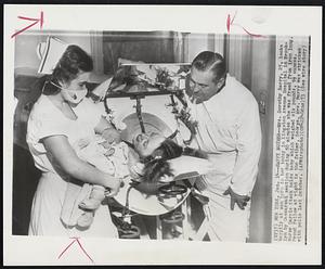 Happy Mother--Mrs. Dorothy Barry, 25, looks happily at son born to her today in Kingston Avenue Hospital in Brooklyn by Caesarean section during 50 minutes she was freed from iron lung. Nurse Darrie Steck holds baby which weighed six pounds, 9 1/2 ounces. Proud fellow at right is the father, George. Mrs. Barry was stricken with polio last October.