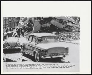 Rubble in Yugoslavia -- Two cars, one badly damaged, stand in street in front of the rubble of a demolished building in Skopje Yugoslavia, after the city was struck by an earthquake yesterday. More than 500 bodies have been recovered from the debris.