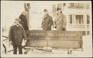 Four people posing by the Spring Valley Farm's sled in winter