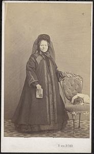 Unidentified woman standing next to a dog on a chair