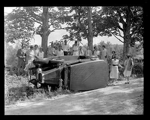 People standing by an overturned car on its side