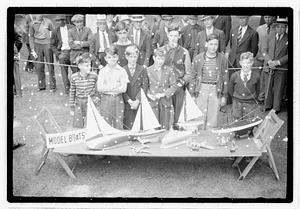 A group of boys behind a collection of model boats