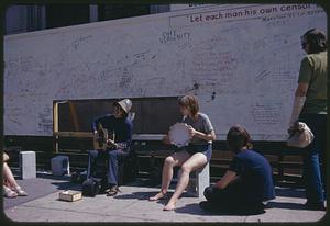 Musicians performing near graffiti billboard, Boston Common