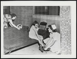 Bedtime--It's bedtime for two little flood refugees tonight at Central school gym being used by the Red Cross to house flood refugees. Left to right: Mrs. R. D. Downing putting her daughter, Roanne, 14 months, to bed, while Joyce Downing, 8, gets an assist from volunteer nurse Doris Carlson.
