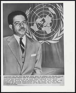 From Police Work to Diplomacy - Omar Adeel, 38-year-old former Scotland Yard detective who now heads Sudan's mission to United Nations, poses by U.N. flag at headquarters in New York City. Adeel, a key member of the powerful Asian-African bloc, has become one of the top delegates at the world organization.