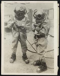 Divers. Daring photographers hope to revolutionize the making of under-water photographs "The hunt for new sensations created the idea for a series of photographs to be made under the Spree River in Berlin. Hitherto all under-water pictures were made in specially prepared glass diving bells. "We, however, desired to experience a new sensation. So, garbed in the usual cumbersome outfit of an under-water diver, we nade the trip to the bed of the Elbe River in this way, carrying a specially constructed camera designed by me--Willie Ruse. We were ably assisted in our task by Diver Boll, who holds a record of 14 hours under water. Of course, before undertaking this following our experiences in photographing ourselves as we parachuted from a plane to Mother Earth, we went to a physician who tested our heart and lung reactions thoroughly. "We had never worn 36-pound shoes before and, as this was a part of our diving equipment, it was necessary to know before we ventured into the water how to use our nether limbs. "When we were finally dressed for our venture below the water our outer garments weighted 320 pounds. By no means is that a weight to be trifled with. "Well, we walked down the ladder gingerly--we assure you--thinking over the final warning of Herr Boll--"once you are in the water we can only give you air; the rest--and that, of course, means your lines--are entirely in your own hands. To an amateur diver, needless to say, this added no pleasures to the adventure. "Though we were only under water 20 minutes before we signalled to those above to hoist us up, it seemed like 20 years." "Just before the final glass was screwed into the helmet, my partner and I examined our specially constructed cameras carefully."