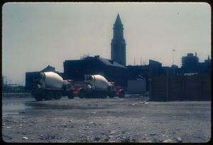 Concrete mixer trucks in foreground, Custom House Tower in background