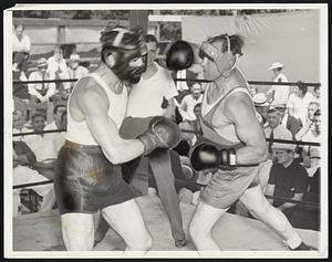 Jack Sharkey, in training for his bout with Joe Louis a week from tonight in the Yankee stadium, shown in a workout at his Orangeburgh, N. Y., camp. Sharkey is about to land a jarring right to the jaw of Don Petrin, one of his sparring mates. That right is the ammunition which Jack intends to use against Louis.