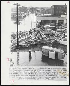 Morning in A Flooded City- The downtown section of this city looked like this after the Horseshoe Dam broke last night under pressure from the rising waters of the Blackstone River. Lumber from nearby yard caused damage to cars in foreground while Social Street (center) still has several feet of water.