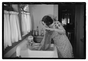 A woman doing laundry at a sink with a washboard