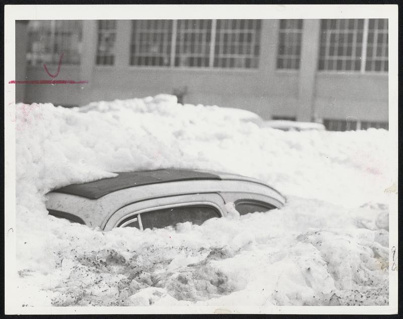 Mystery Car at the rear of 1247 Commonwealth Ave., Boston, is buried to the roof in snow. Residents say it has been there since November. A boy who burrowed through the snow found the car had Rhode Island plates.