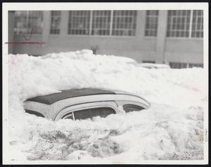 Mystery Car at the rear of 1247 Commonwealth Ave., Boston, is buried to the roof in snow. Residents say it has been there since November. A boy who burrowed through the snow found the car had Rhode Island plates.