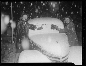 Women clean snow off car
