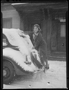 Woman clearing auto during snowstorm