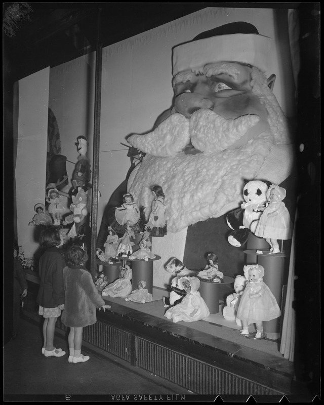 Girls gaze longingly at dolls in Christmas display