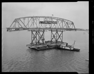 Tug pushing barge with section of Long Island viaduct
