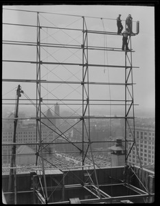 Workers building sign on roof of building near Park Square