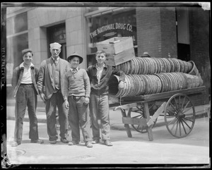 Four men in front of the National Drug Company with pushcart loaded with baskets