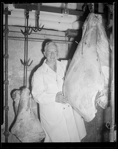 Butcher examines beef in cold room