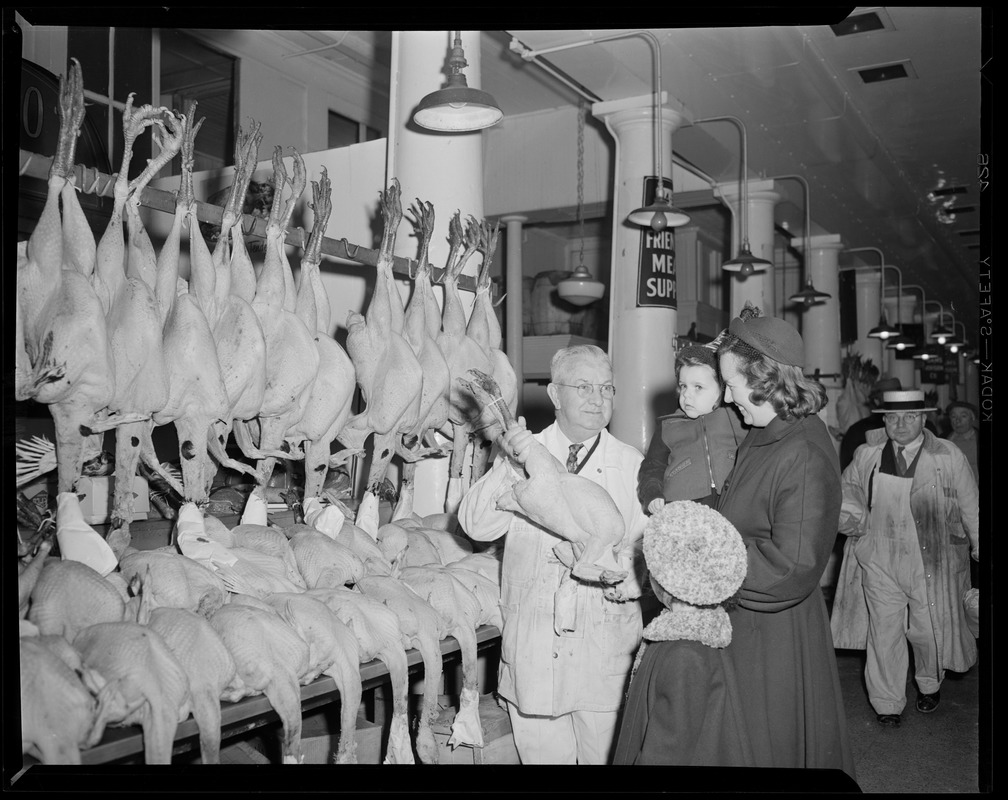 Mr. Kelley shows array of Thanksgiving turkeys to mother and child, Thresher & Kelley Market, Faneuil Hall