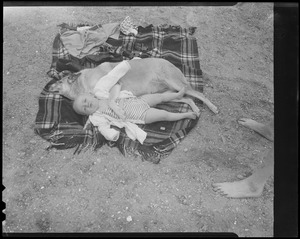 Child and dog relax on beach in South Boston