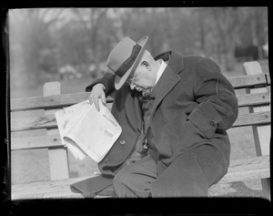 Man on bench reading paper