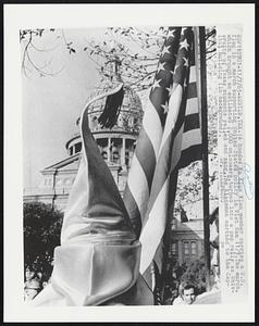 A hooded Ku Klux Klan member carries a U.S. flag in a march supporting Unite States policy in Vietnam 11/7.The march, which brought an estimated 2,000 onlookers, turned into a pep rally as University of Texas students yelled and sang. The Klansmen marched to the Capitol building (in background).