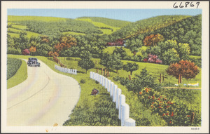 Car driving down a road, hills to the right