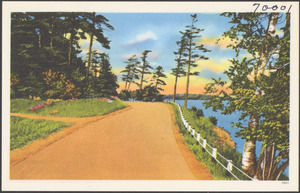 A road with a guard rail and body of water to the right