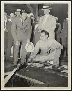 Range Oil for wartime emergency was provided in drum shipments in box cars by White Fuel Corp. when tankers and tank cars were unavailable. Here Gov. Robin and Police Commissioner Sullivan watch the pouring of range oil into a special trough leased on Southampton street for householder distribution.