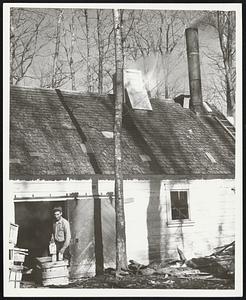 Another Case of State of Main Maple Syrup. Warren Voter, in the doorway of his sap house, in Farmington, is shown completing another case of State of Maine syrup. Voter packs his syrup in quart and gallon cans bearing the State of Maine Blue, White and Red trademark of quality