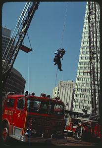 People, probably firemen, descending down from an aerial ladder by rope, Boston City Hall Plaza