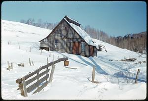 Barn and fence on snow-covered hill