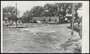 Streets Becomes Canal-One of the heavier traveled streets in Salt Lake City was converted into a canal with sandbags to carry off flood water from melting snow in mountains. This water flowed into Jordan River which was flooding in west part of city.