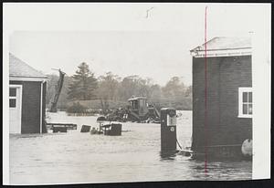 Familiar Scene to most New Englanders by now is a flooded yard. This is the road machinery depot of a Westbrook, Me., company after a 10-inch rainfall.
