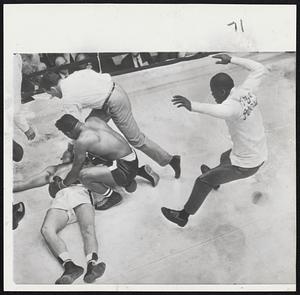 Floyd Patterson and a referee stand over a prone Ingemar Johansson as another man jumps into the ring