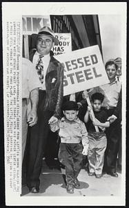 Detroit – Young Pickets – Ronald Weiss, (second from left) is shown walking the UAW-CIO Ford Motor strike picket line, here today, with his father Lester Weiss, (left) a press steel worker at the Ford plant. The little fellow carrying the sign is Sandy Mugurian, son of another UAW picket.